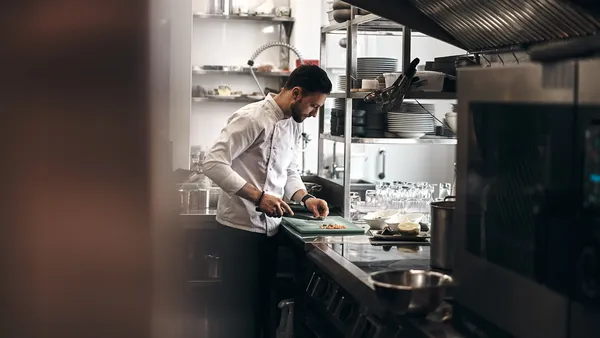 Profesjonelt restaurantkjøkken med kokk som jobber ved induksjonskomfyr