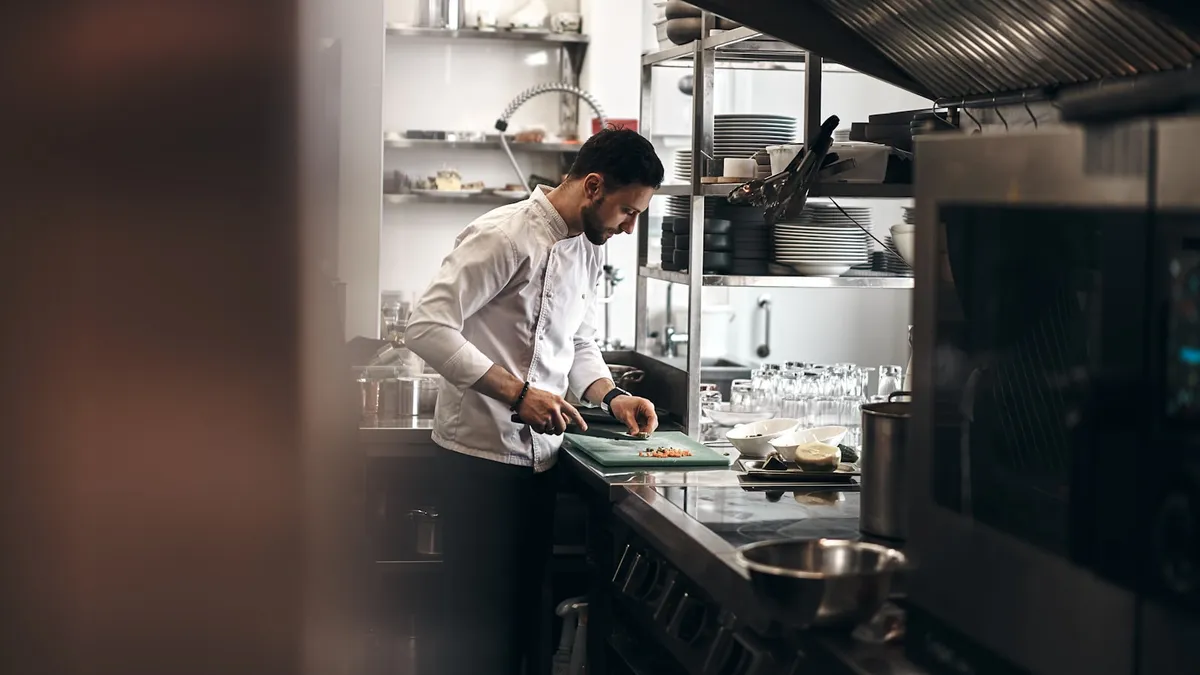 Profesjonelt restaurantkjøkken med kokk som jobber ved induksjonskomfyr