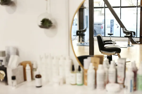 Norsk frisør viser kunde profesjonelle hårpleieprodukter i salongens butikk-område