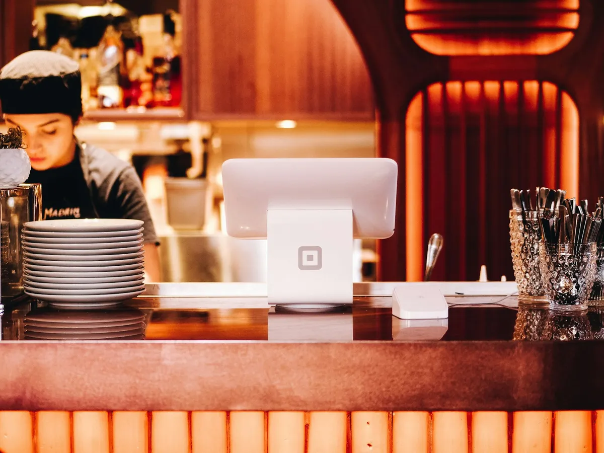 Restauranteier som fører regnskap på laptop ved kassa i restaurantkjøkken